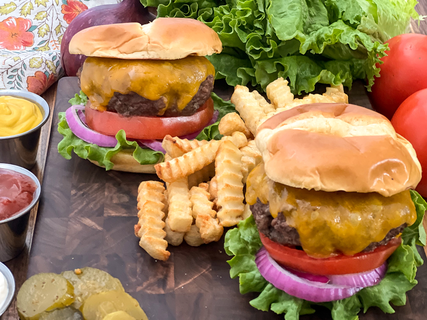 Two cheeseburgers in a bun with lettuce, onion, and tomato with french fries between them.