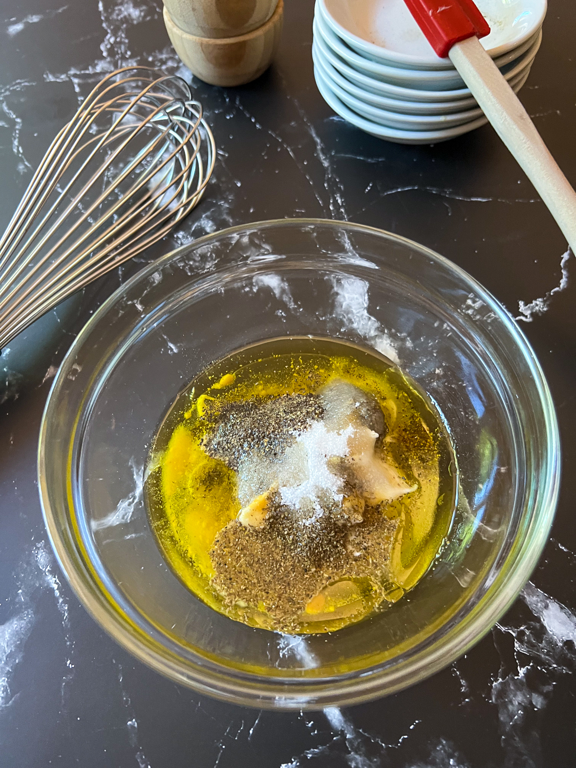 The dry seasonings, apple cider vinegar, and olive oil have been added to a small bowl.