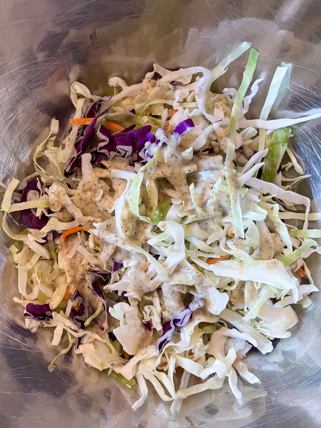 Half of the cabbage mixture and half of the dressing in a stainless steel bowl. 