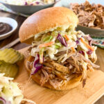 Smoked pulled pork in a bun topped with coleslaw.