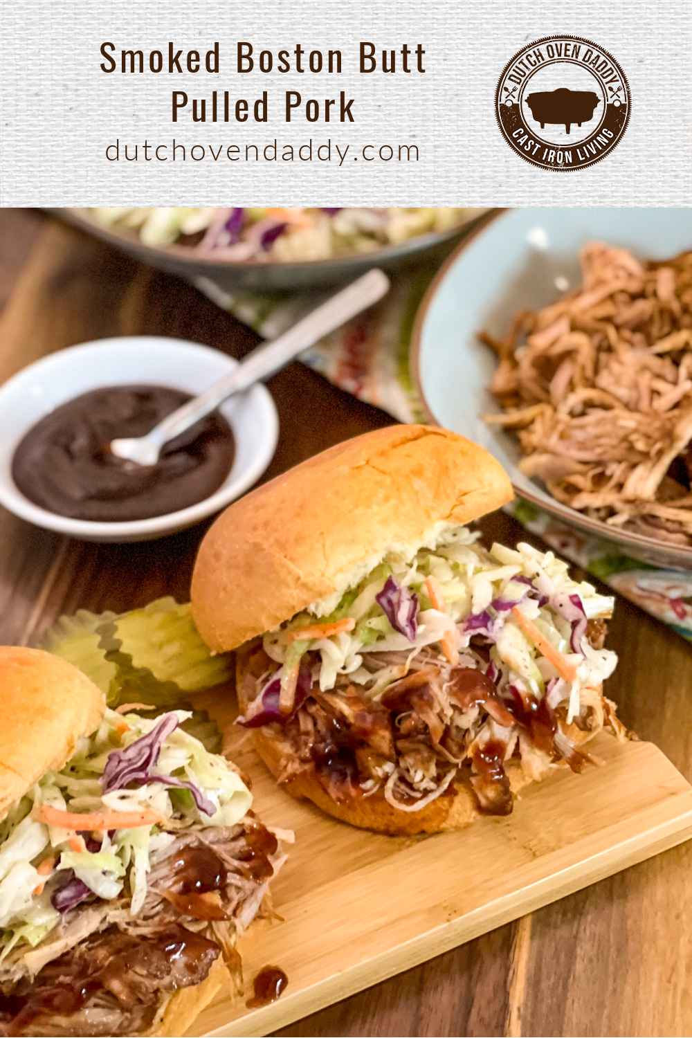Branded image of Smoked Boston Butt Pulled pork. Two sandwiches drizzled with barbecue sauce and topped with coleslaw inside buns.