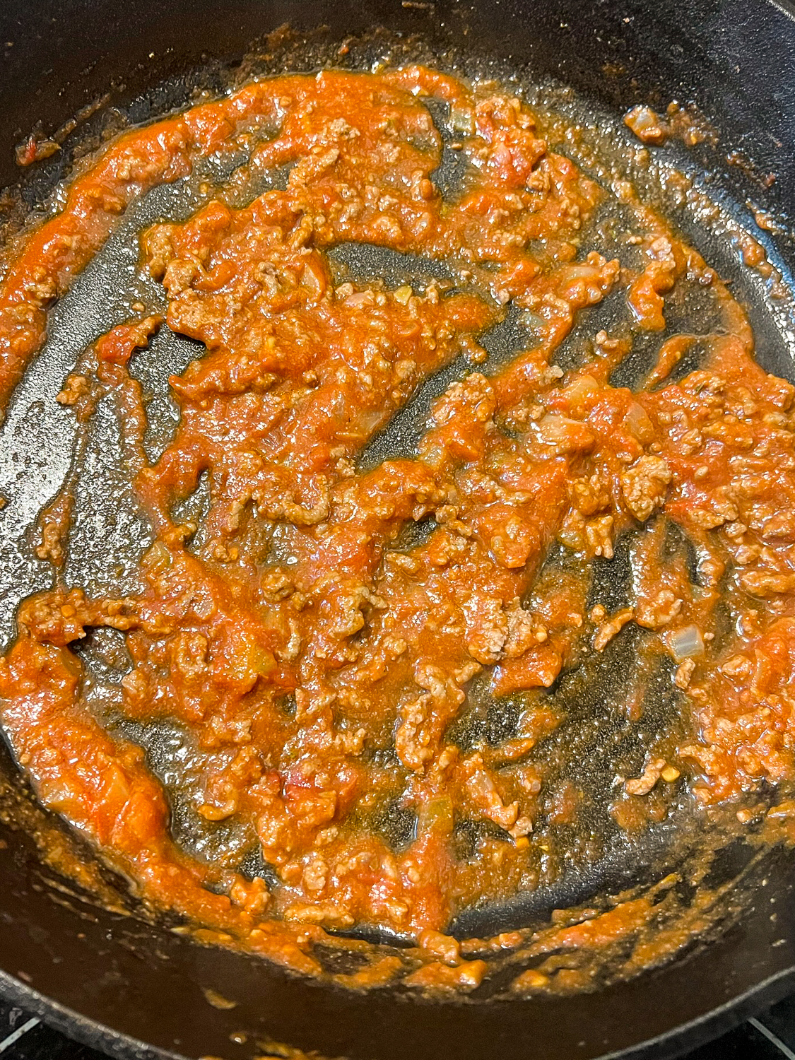 A small amount of meat sauce added to the bottom of the skillet.