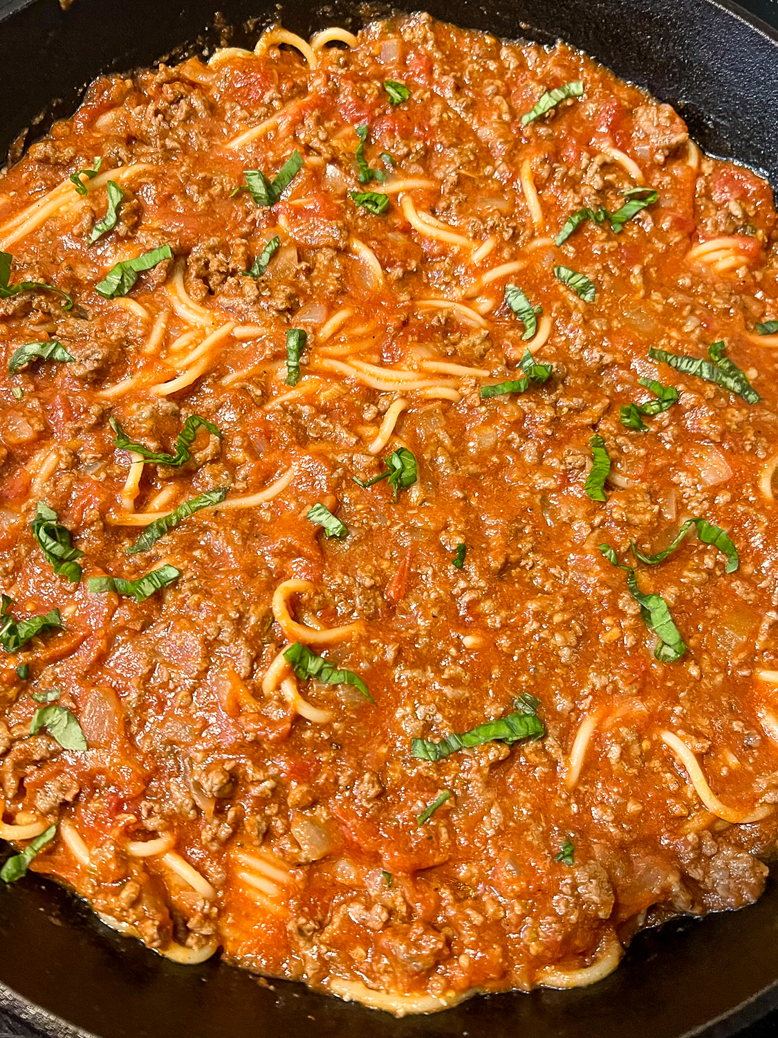Freshly chopped basil atop the meat sauce.