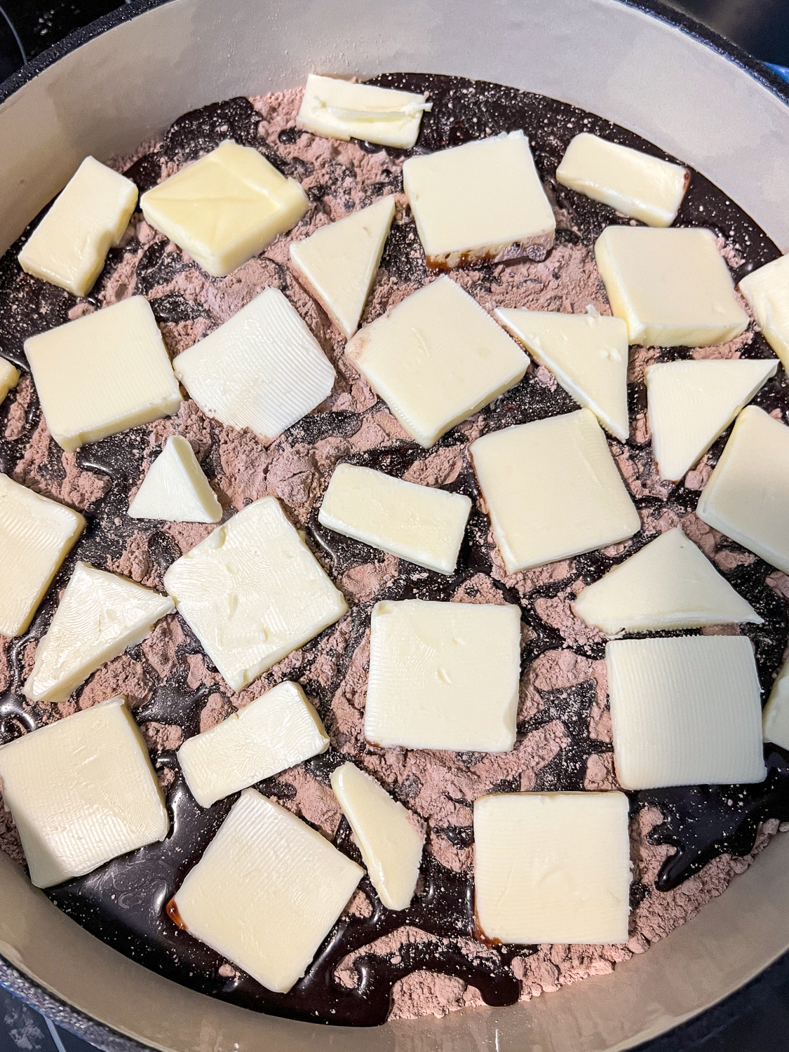 Butter pats dot the entire surface of the cake in the dutch oven.