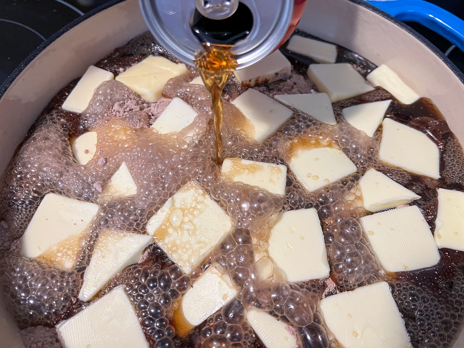 The can of cola is being slowly poured over the cake.