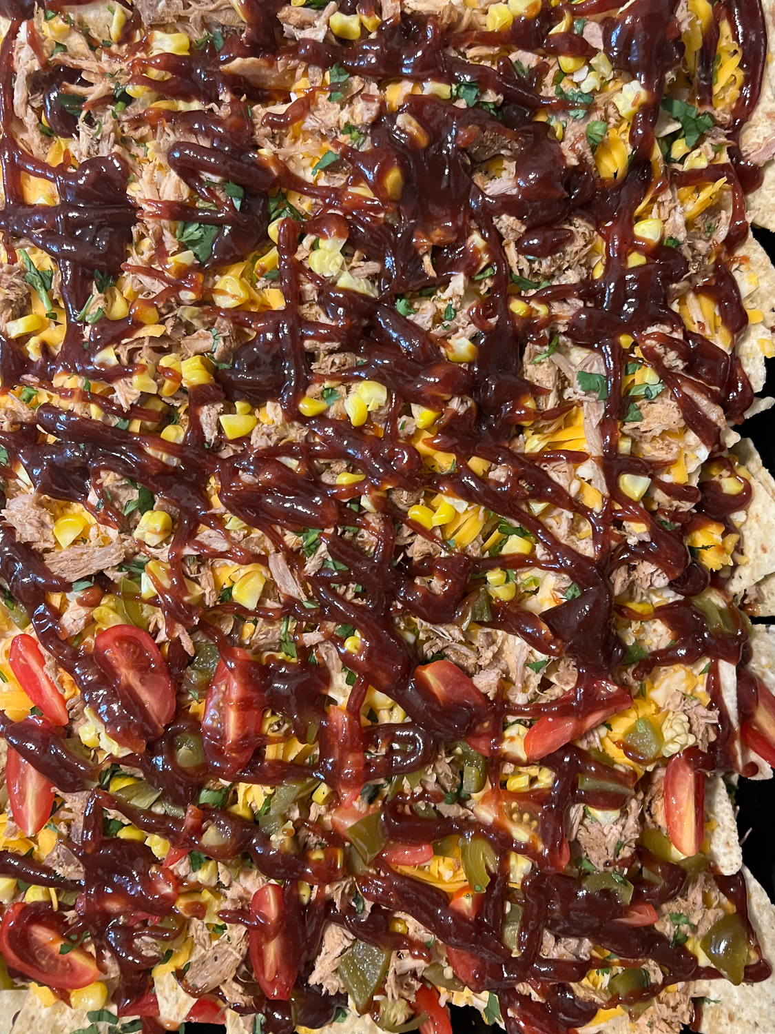 Roasted corn and cilantro over the pork and cheese, then half the pan with pickled jalapeños and diced tomatoes, and the entire thing heavily drizzled with barbecue sauce.