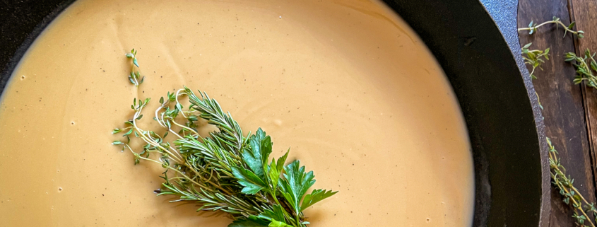 Close up of turkey gravy in the skillet garnished with fresh herbs.