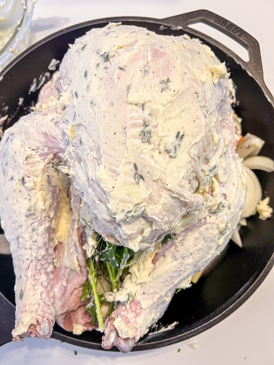 Herb butter has been applied all over the surface of the turkey.