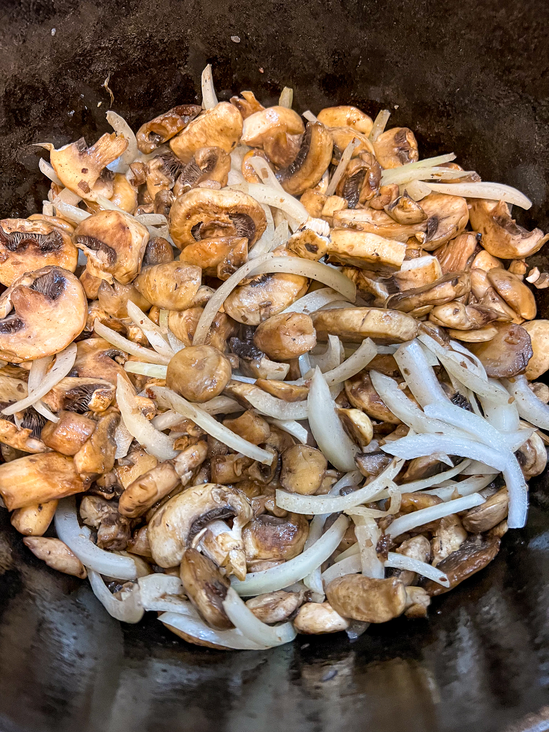 Onions and mushrooms sauteeing in the dutch oven.