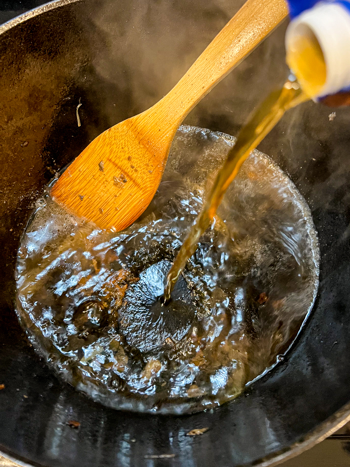 Beef broth being added to deglaze the dutch oven.