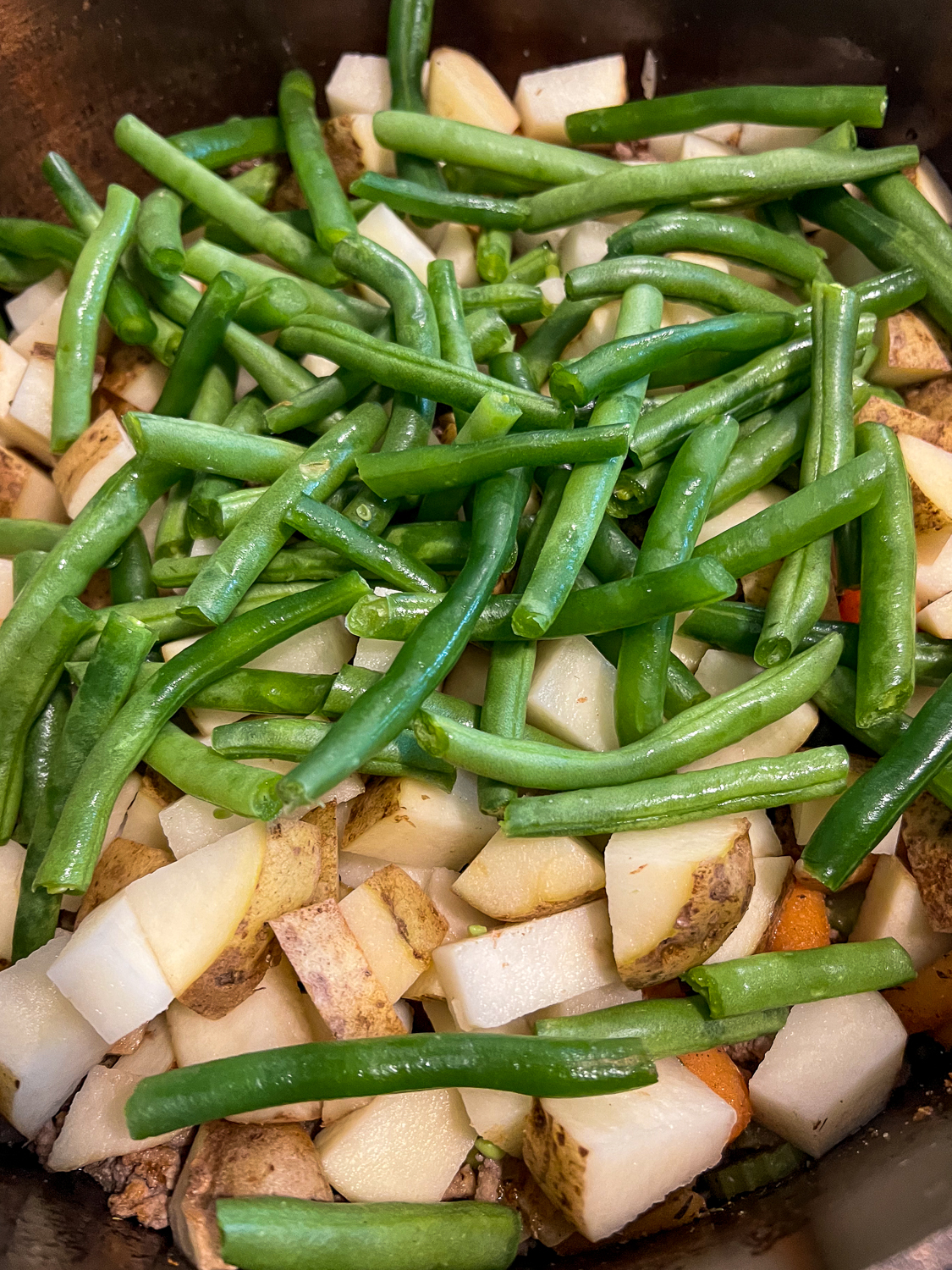 Green beans and potatoes tossed into the dutch oven.