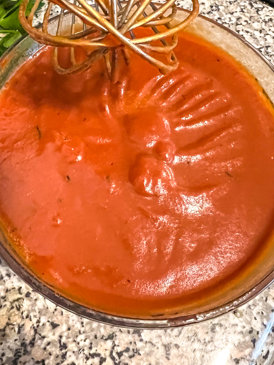 Tomato paste and broth have been whisked together in a small glass bowl.