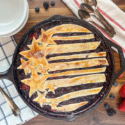 Red, white, and blue berry cobbler baked in a round 12-inch cast iron skillet.