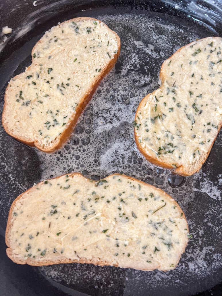 Buttery garlic bread toasting in a cast iron skillet.