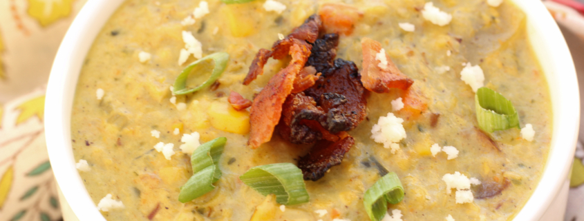 Roasted Poblano Corn Chowder in a white bowl garnished with queso fresco, bacon crumbles, and green onions.