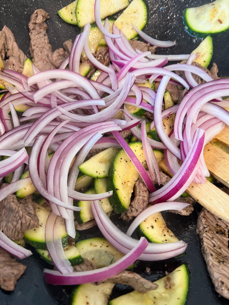 Sliced red onions tossed into the wok with beef and zucchini.