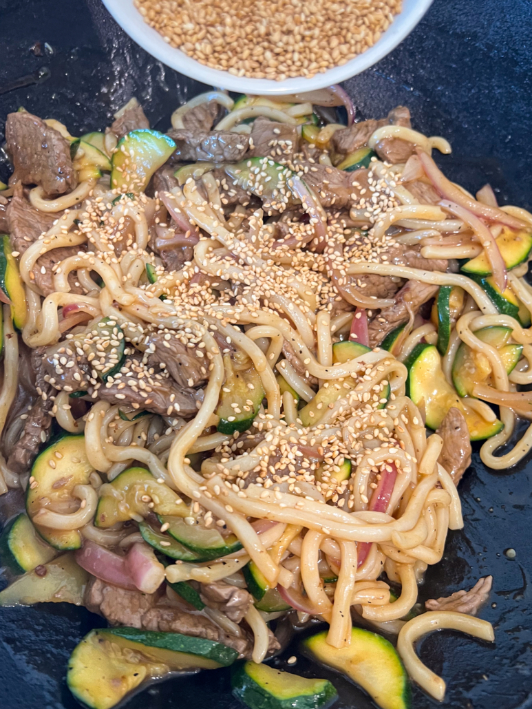 Teriyaki sauce and sesame seeds being added to the the stir fry.