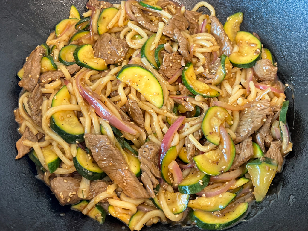 The teriyaki beef udon noodle stir fry is done and ready to be served from the cast iron wok.