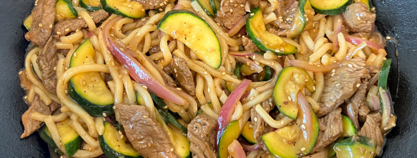 The teriyaki beef udon noodle stir fry is done and ready to be served from the cast iron wok.