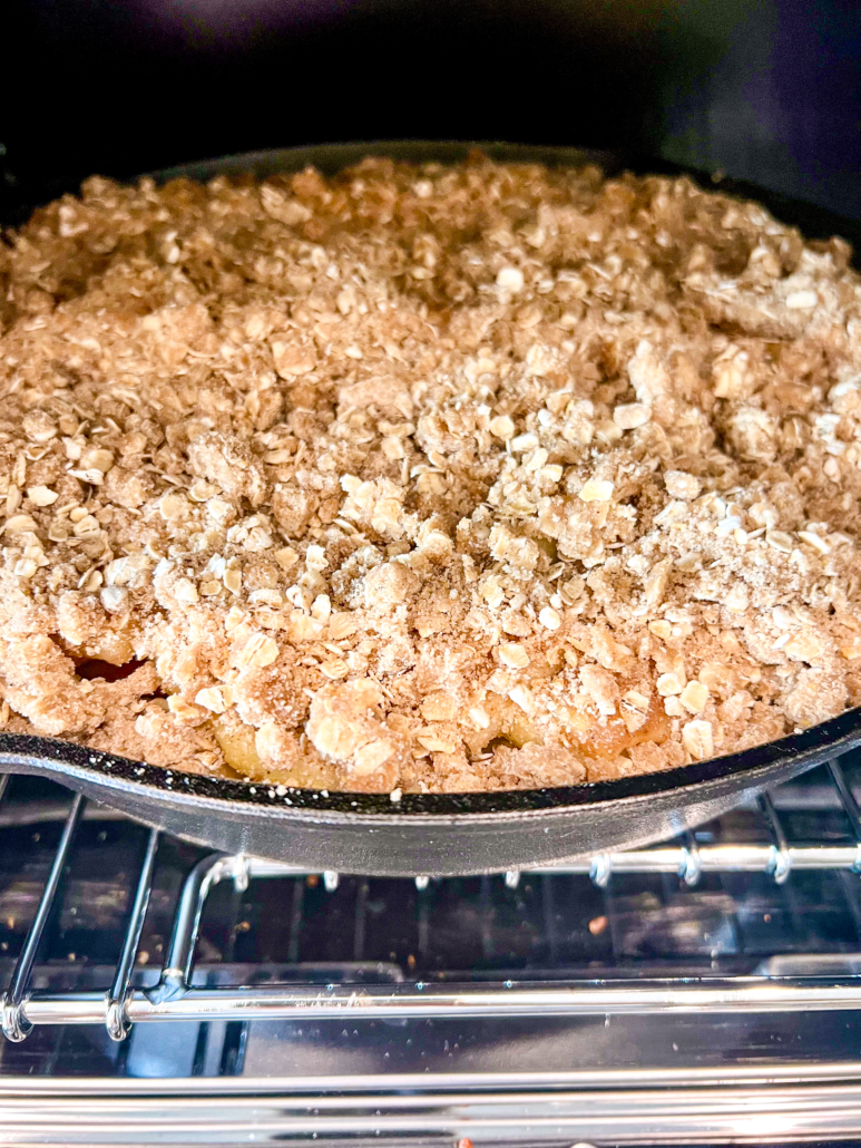 Cast iron skillet apple crisp going into the oven to bake.