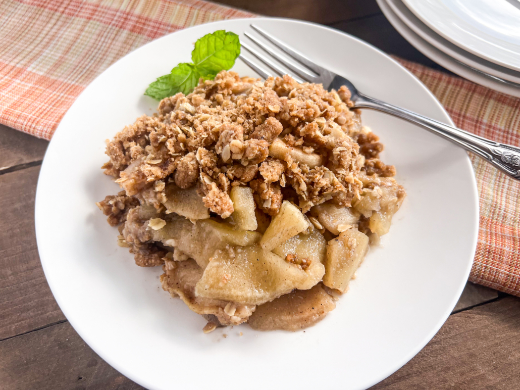 A serving of apple crisp on a white plate.