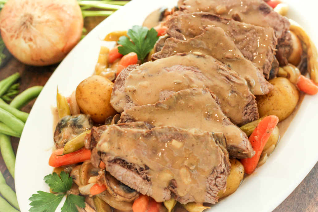 Slices of beef roast on top a bed of vegetables covered with mushroom whiskey gravy.