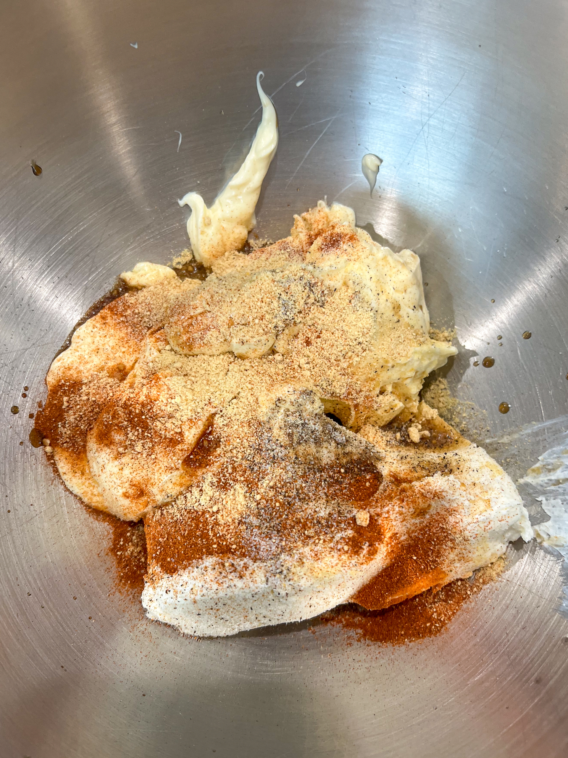 Seasonings, mayo, worcestershire sauce, and cream cheese added to a stainless steel mixing bowl.