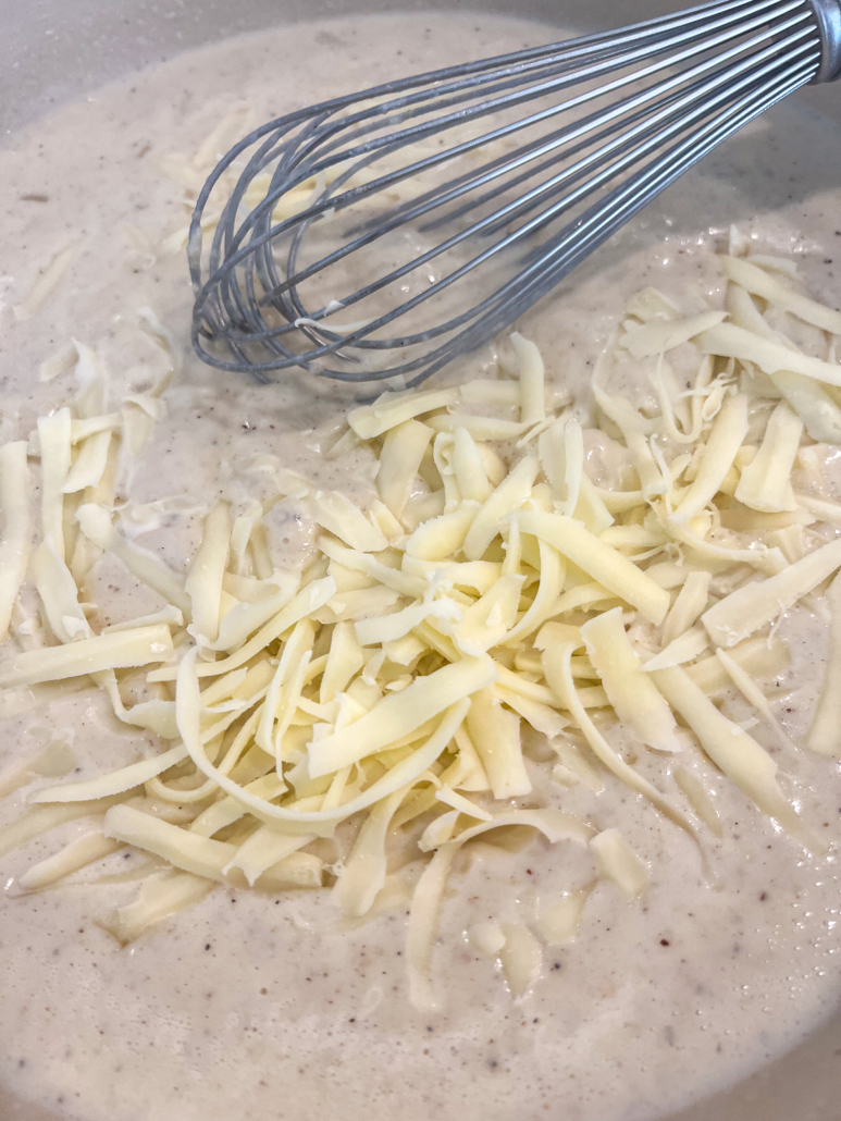 Shredded mozzarella cheese being incorporated to the cream sauce.