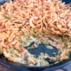 Bacon green bean casserole in a cast iron skillet with a couple portions spooned out.