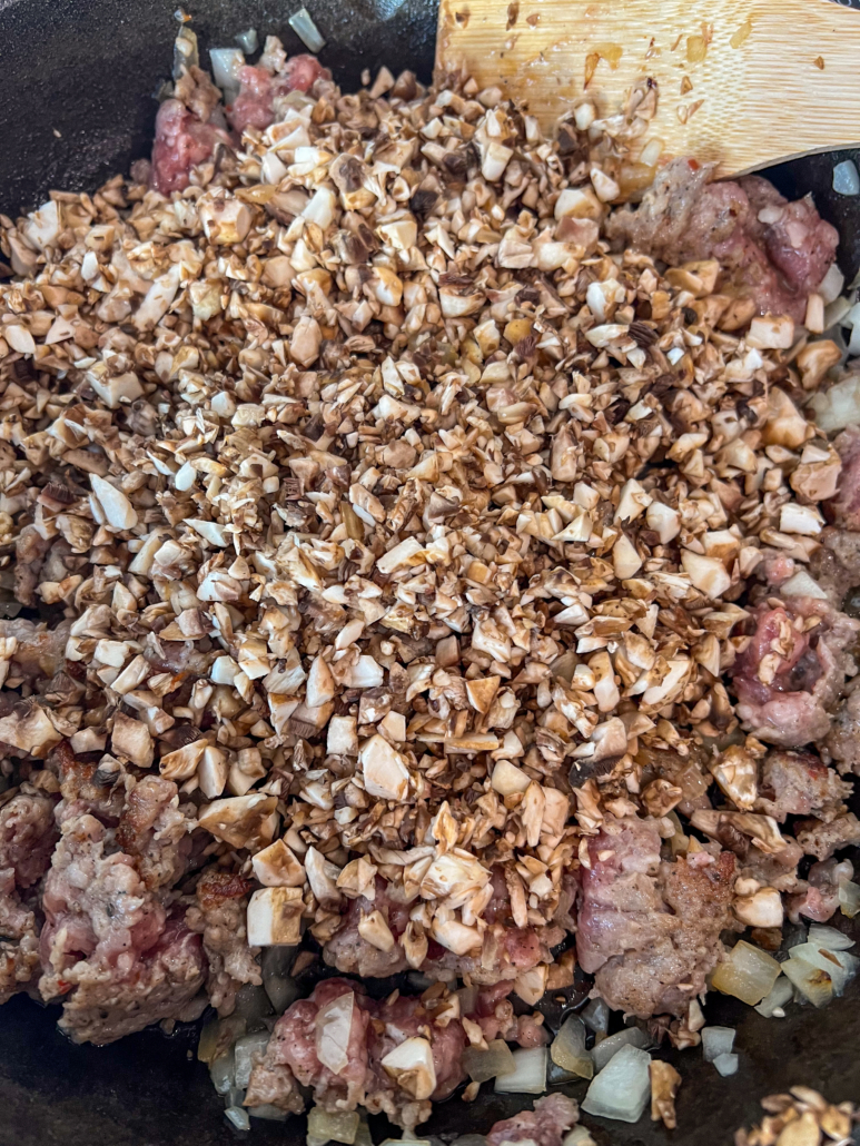 Finely diced mushrooms added to the meat and onions in the skillet.