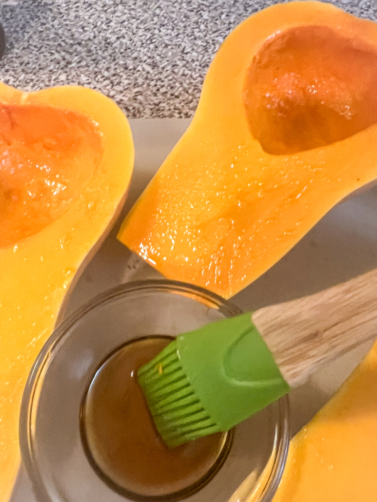 Olive oil and maple syrup being brushed on the exposed flesh of the squash.