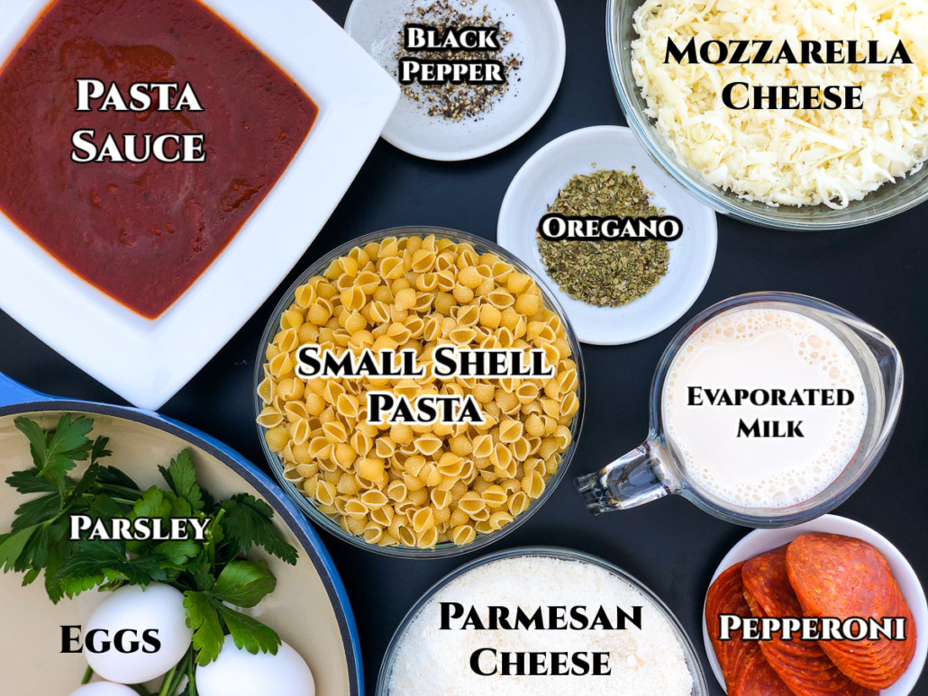 Ingredients to make Pizza Pasta in the Dutch oven: Pasta sauce, black pepper, mozzarella and parmesan cheeses, oregano, evaporated milk, pepperoni, small shell pasta, fresh parsley, and eggs.