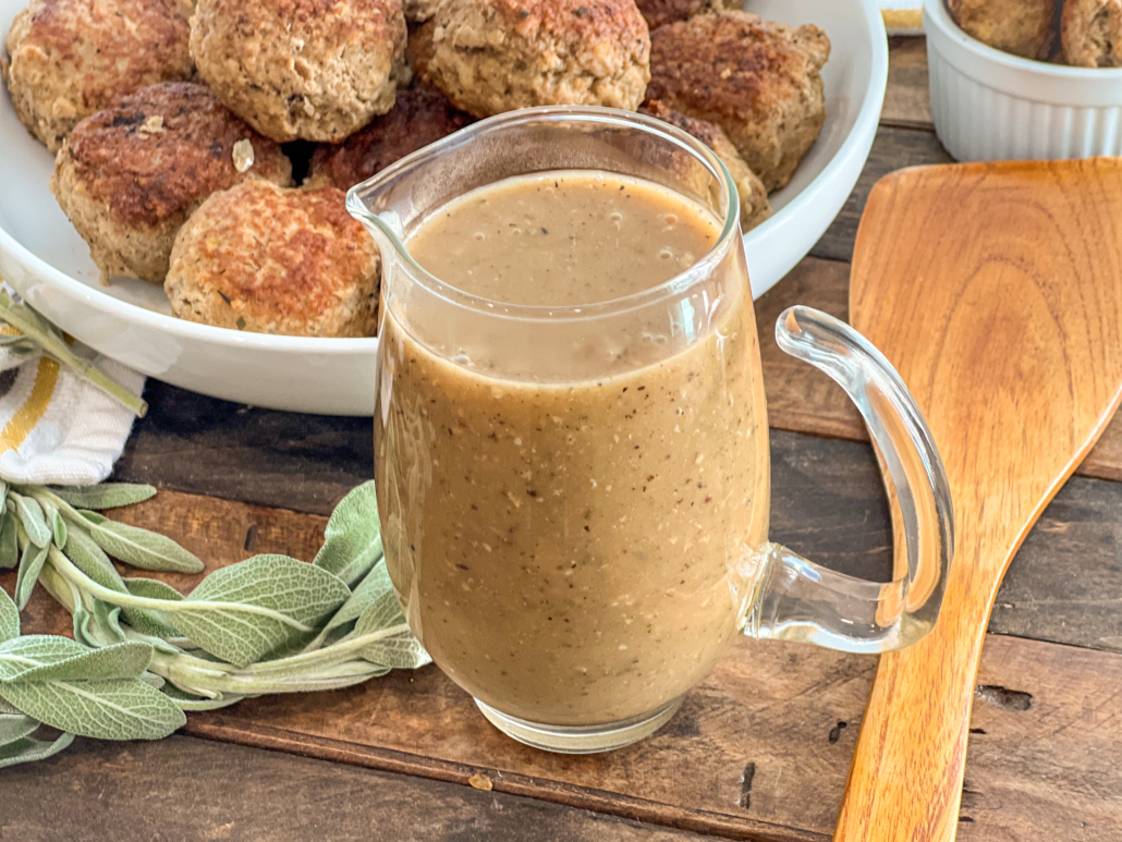 Easy skillet gravy is in a glass gravy pitcher with meatballs in the background.