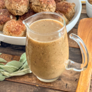 Easy skillet gravy is in a glass gravy pitcher with meatballs in the background.