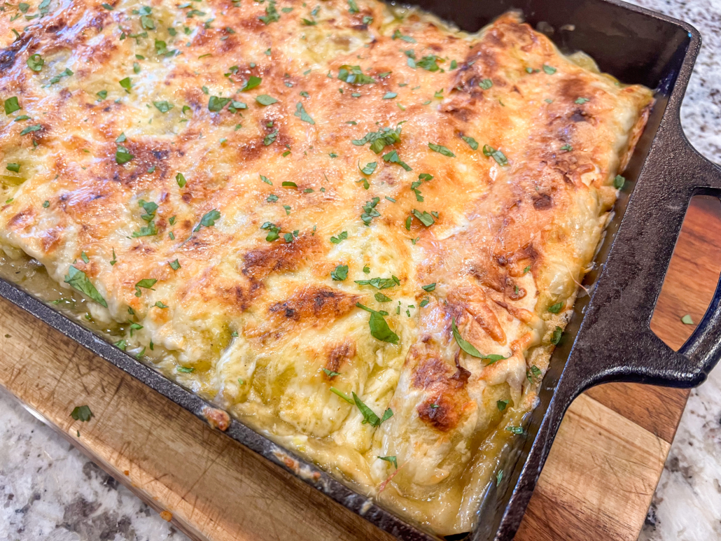 Fresh from the oven pan of creamy green chile chicken enchiladas that have been garnished with fresh cilantro.