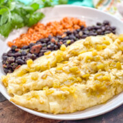 Plated serving of 3 green chile chicken enchiladas with black beans and rice.