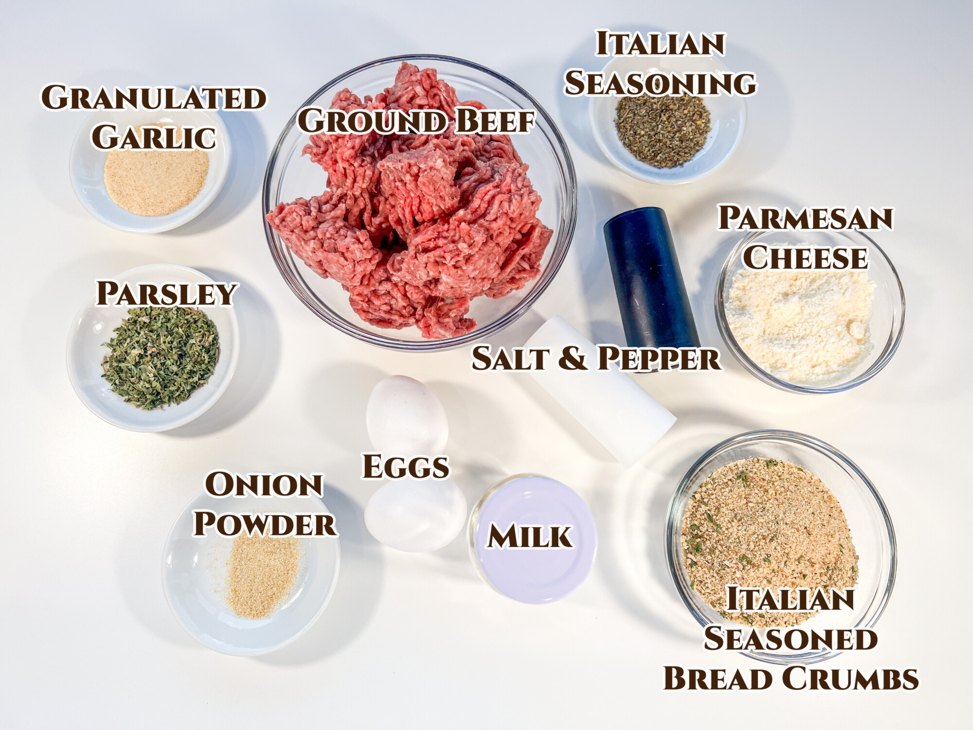 Ingredient collage with text overlay of all the recipe ingredients: granulated garlic, parsley, onion powder, eggs, milk, salt, pepper, Italian seasoned bread crumbs, Parmesan cheese, and Italian seasoning blend.