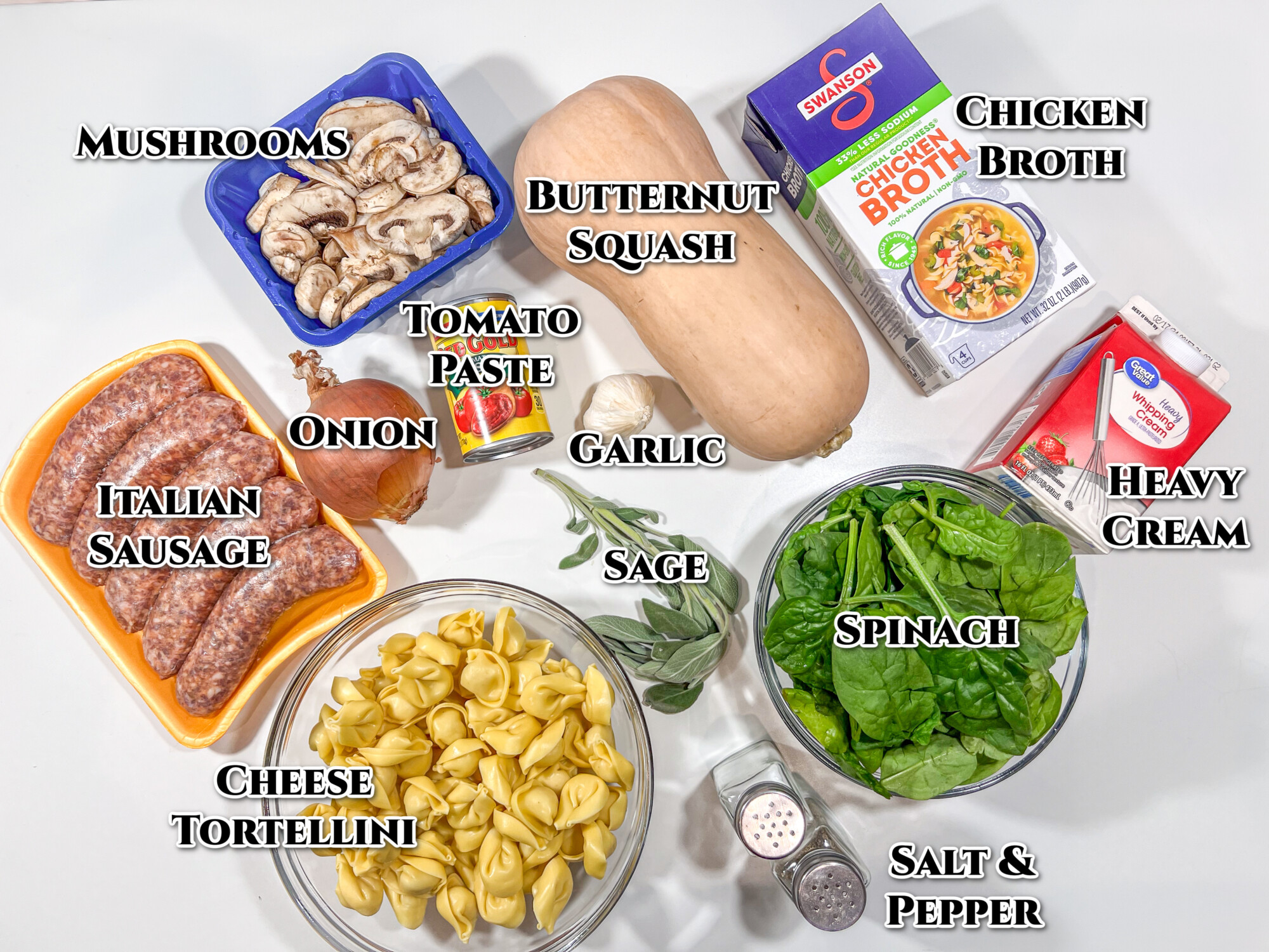 Labeled image of ingredients for the recipe: mushrooms, butternut squash, chicken broth, cream, spinach, salt, pepper, sage, garlic tomato paste, onion, cheese tortellini, and Italian sausage.