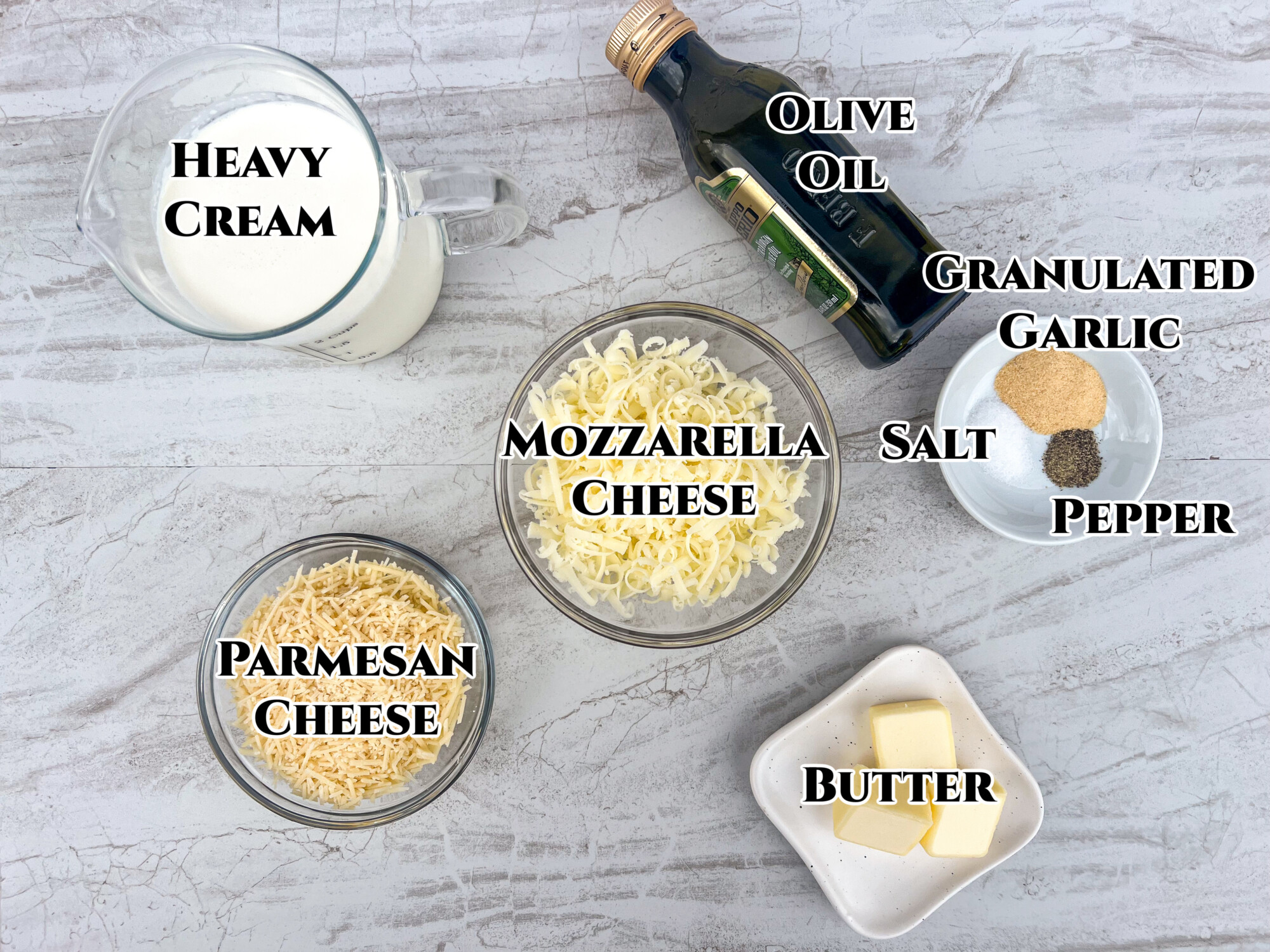 Labeled image of ingredients to make alfredo sauce: heavy cream, olive oil, granulated garlic, salt, pepper, butter, mozzarella cheese, and Parmesan cheese.