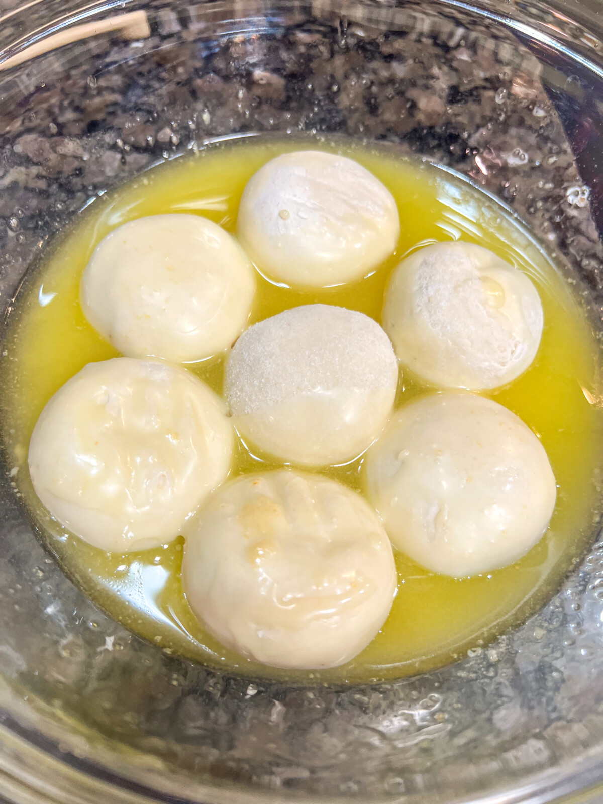 Frozen rolls being dipped into melted butter.