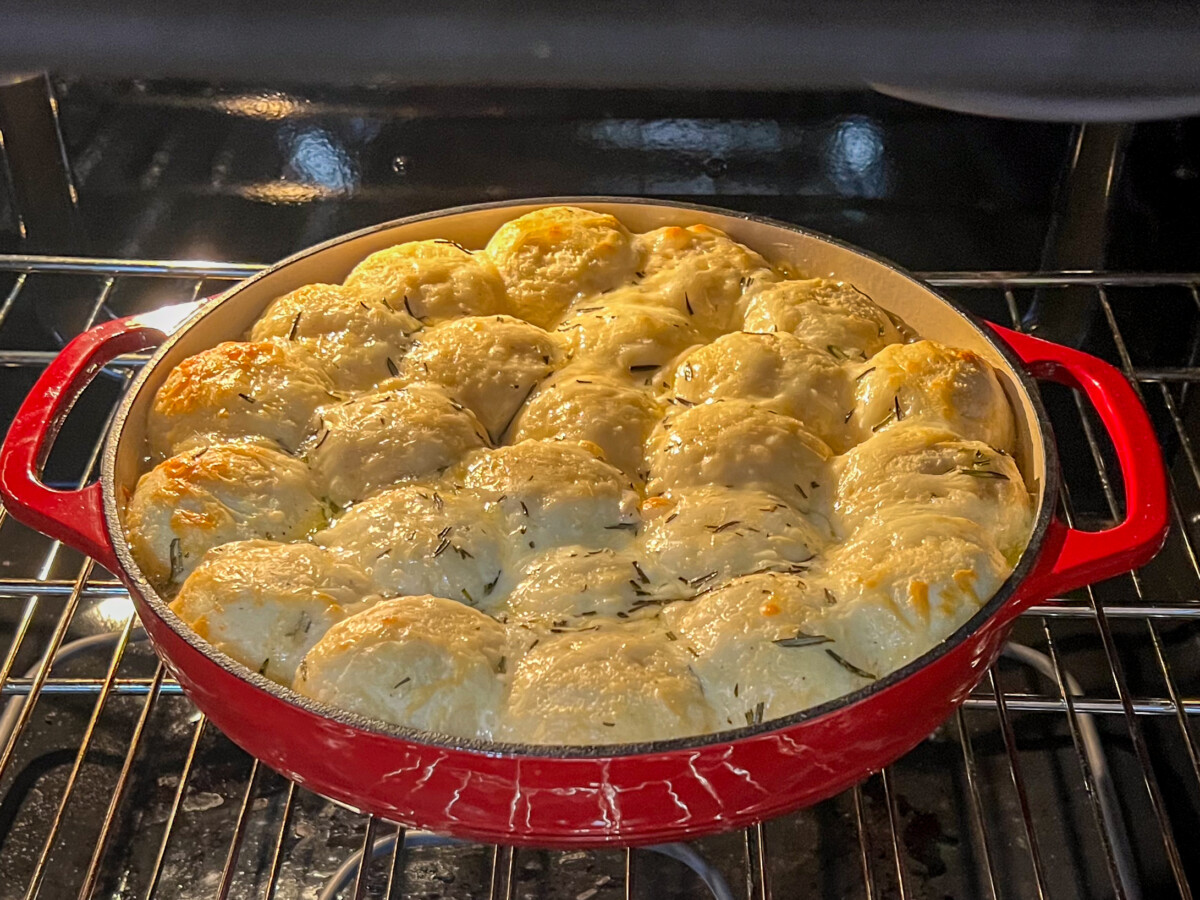 Cheesy Alfredo Pull Aparts in the oven cooking in an enameled Dutch Oven uncovered.