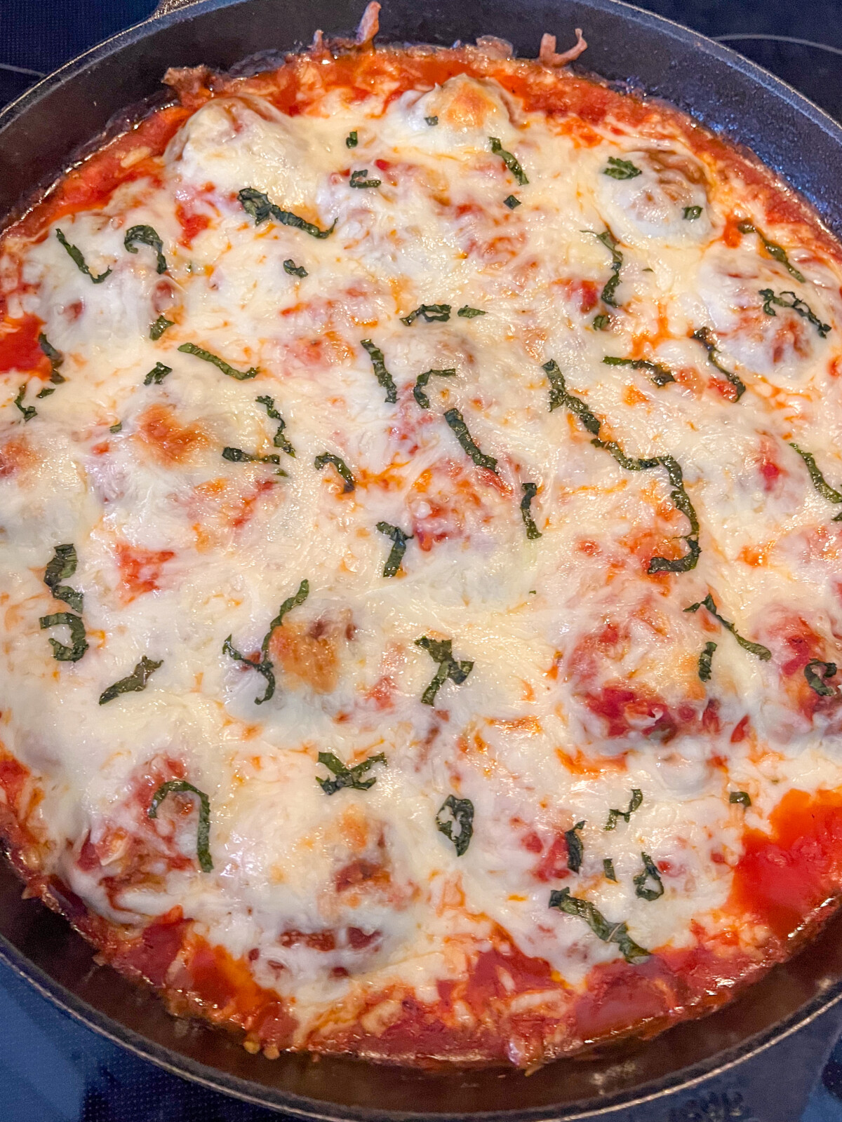 Fresh from the oven cheesy, saucy meatballs in a skillet.