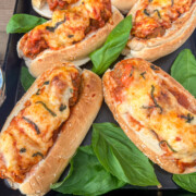 Meatballs sub sandwiches ready to be served with fresh basil leaves garnishing the baking pan.