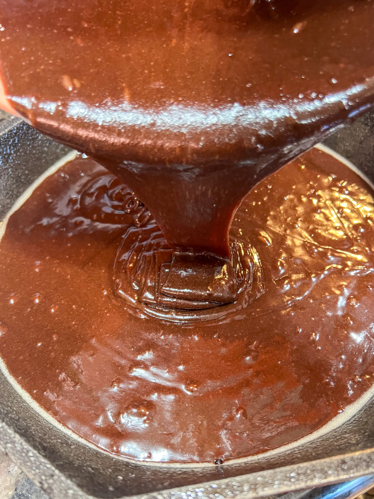 The brownie batter being poured into a prepared pan.