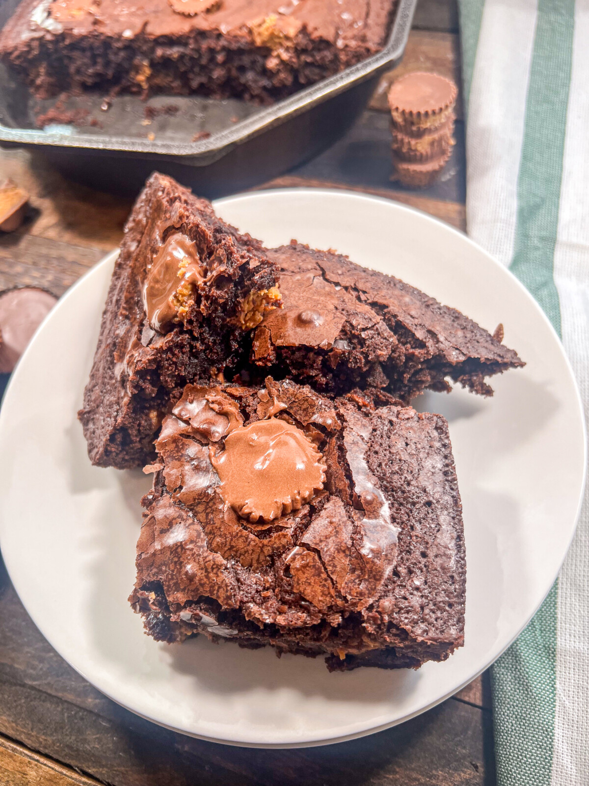 A plateful of brownies with peanut butter candy with the rest in the skillet in the background.