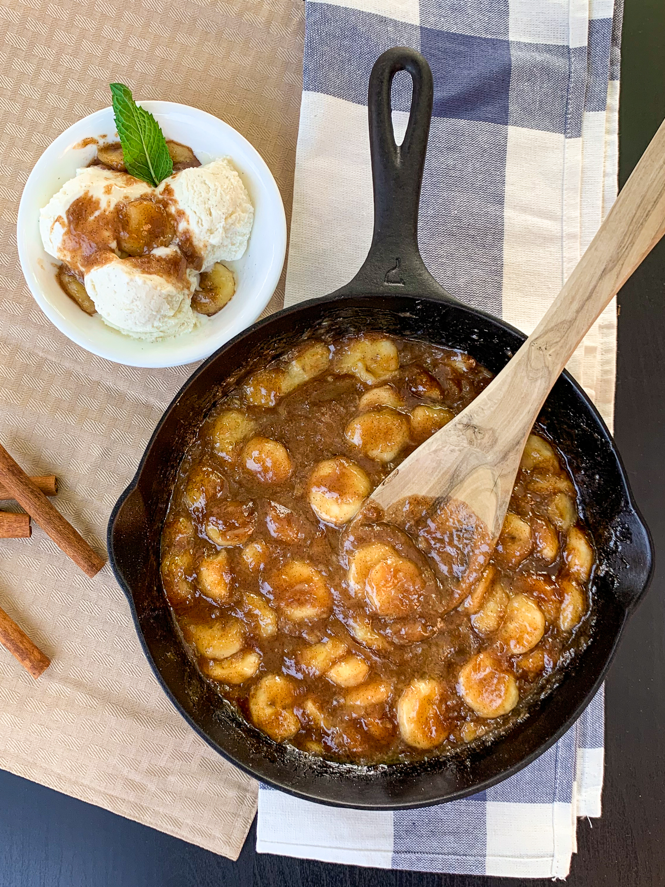 Bananas Foster made in a cast iron skillet with a portion served over vanilla ice cream.