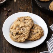 Oatmeal chocolate chip cookies stacked on a white plate.