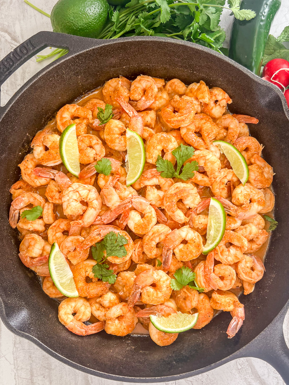 Chili lime shrimp served in a cast iron skillet with fresh lime wedges and cilantro.