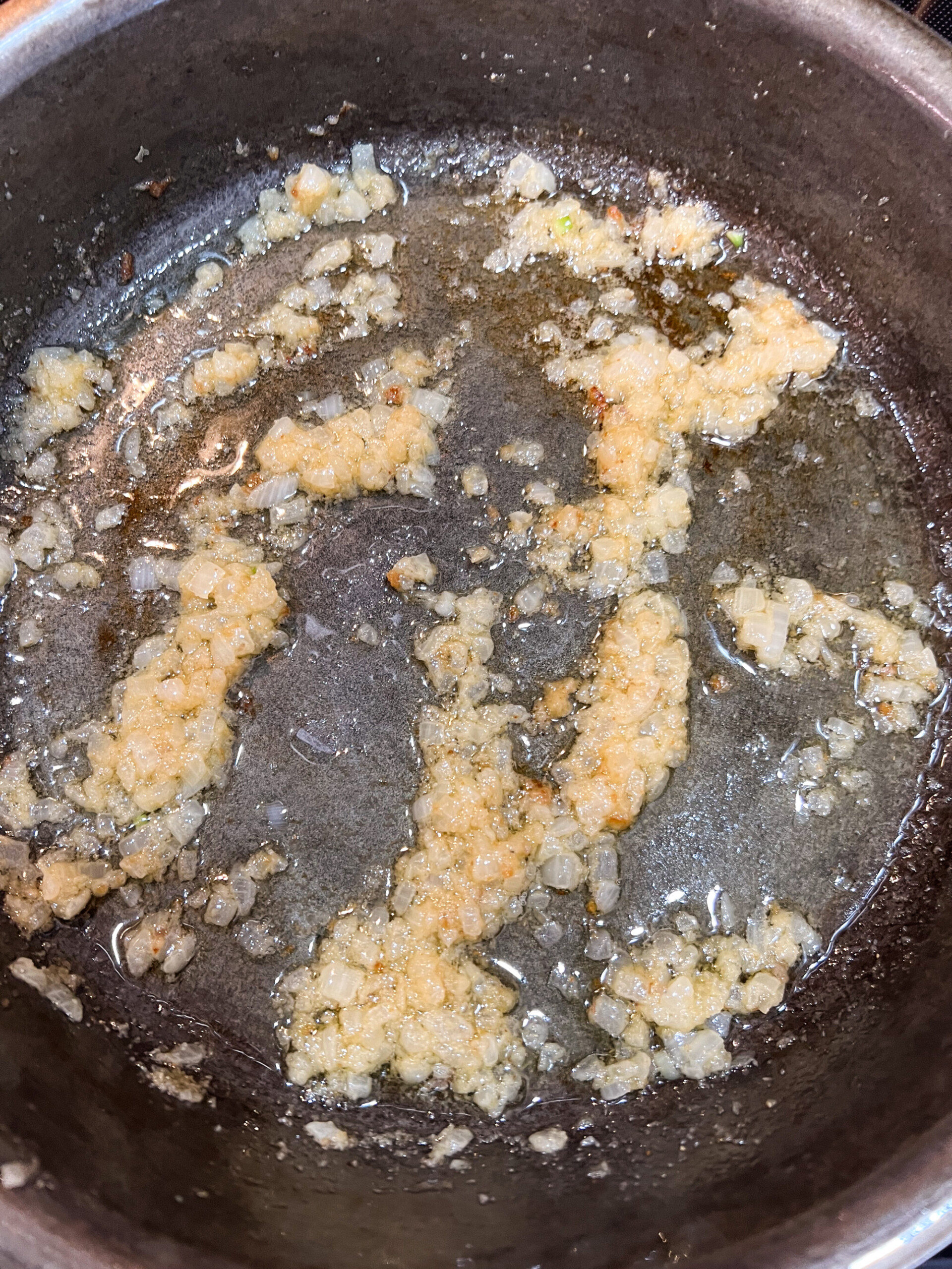 Onions and butter being cooked in a cast iron skillet.