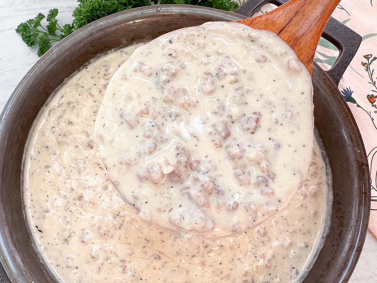 Easy Sausage Gravy in a cast iron skillet ready to be served with a wooden spoon.
